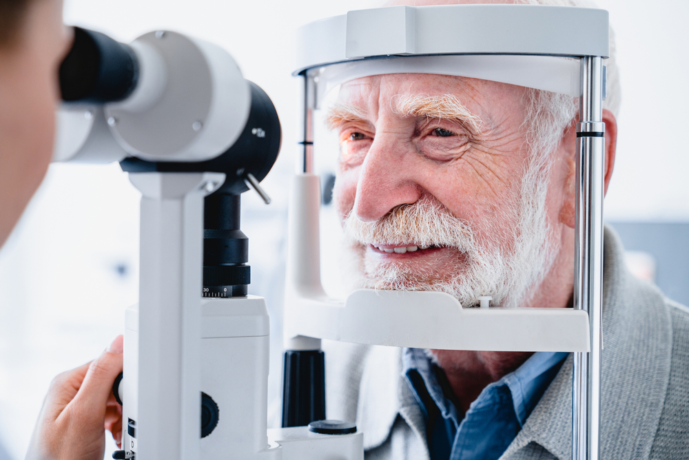 Close up photo of smiling senior male patient during sight examination - Diabetic Eye Exams Huntington Beach