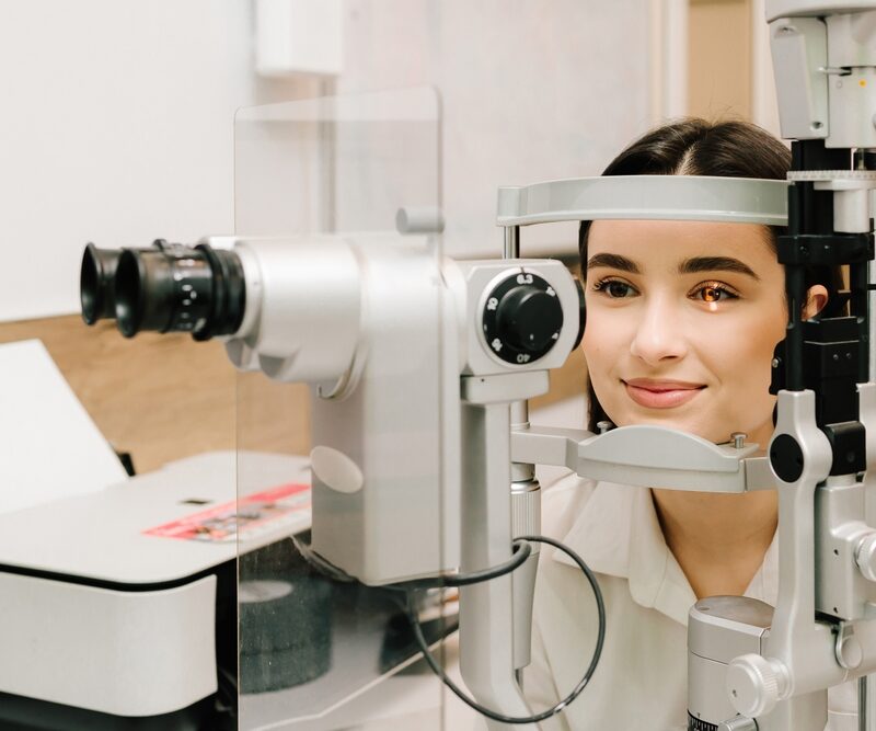 Ophthalmologist with slit lamp examines eyes and cornea of woman. Ophthalmologist illuminates eye of patient with light from slit lamp to diagnose the eyes and cornea