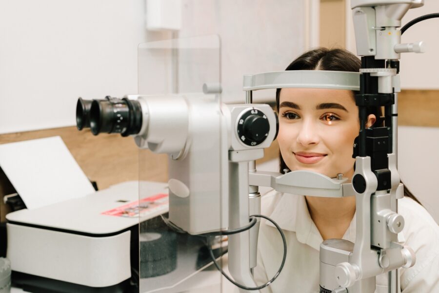Ophthalmologist with slit lamp examines eyes and cornea of woman. Ophthalmologist illuminates eye of patient with light from slit lamp to diagnose the eyes and cornea