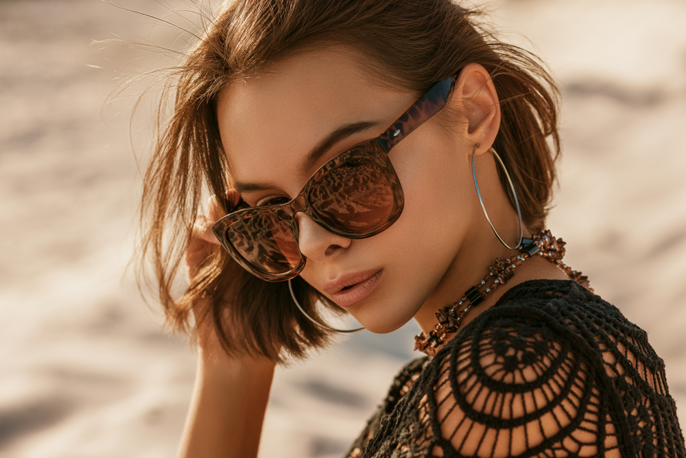 Woman wearing sunglasses doing stop sign - See Breeze Optometry