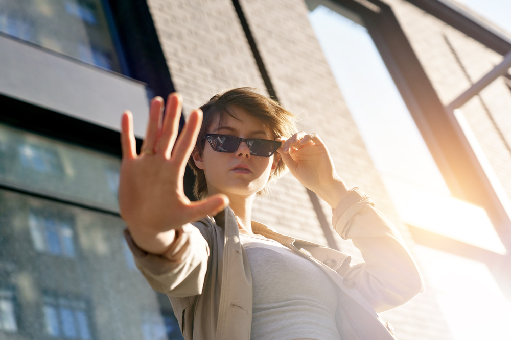 Woman wearing sunglasses doing stop sign - See Breeze Optometry Woman wearing sunglasses doing stop sign - See Breeze Optometry