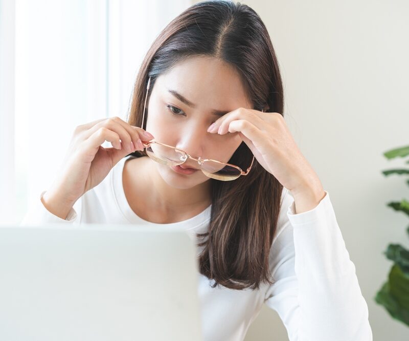 Eye problem concept, fatigue asian young woman tired eyes, irritated rubbing eye dry relief vision pain after work on laptop computer, eye strain, hand holding glasses, suffer migraine, bad blurry.