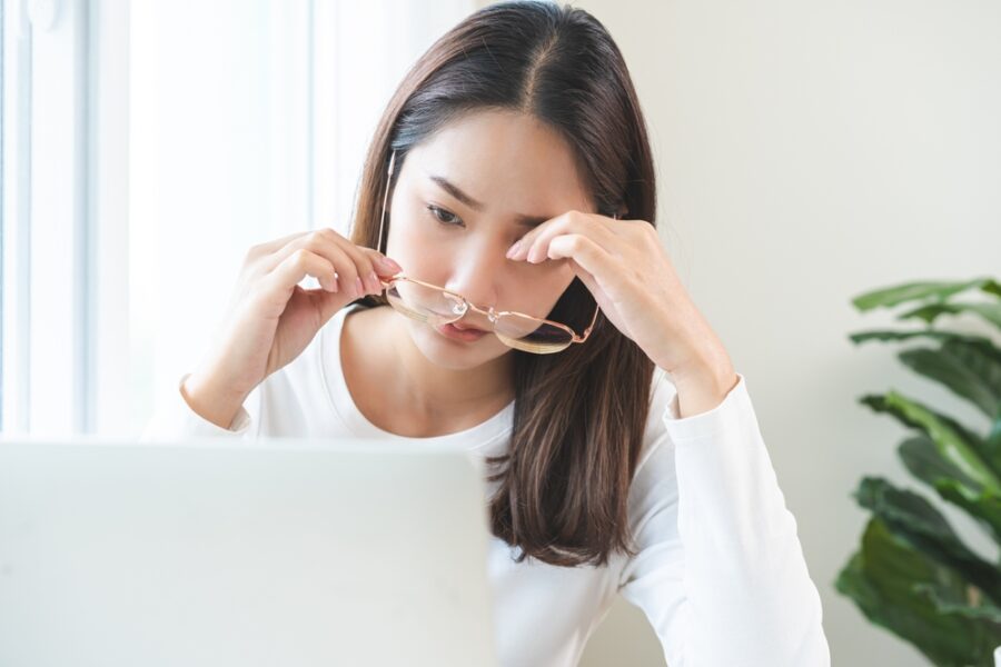 Eye problem concept, fatigue asian young woman tired eyes, irritated rubbing eye dry relief vision pain after work on laptop computer, eye strain, hand holding glasses, suffer migraine, bad blurry.
